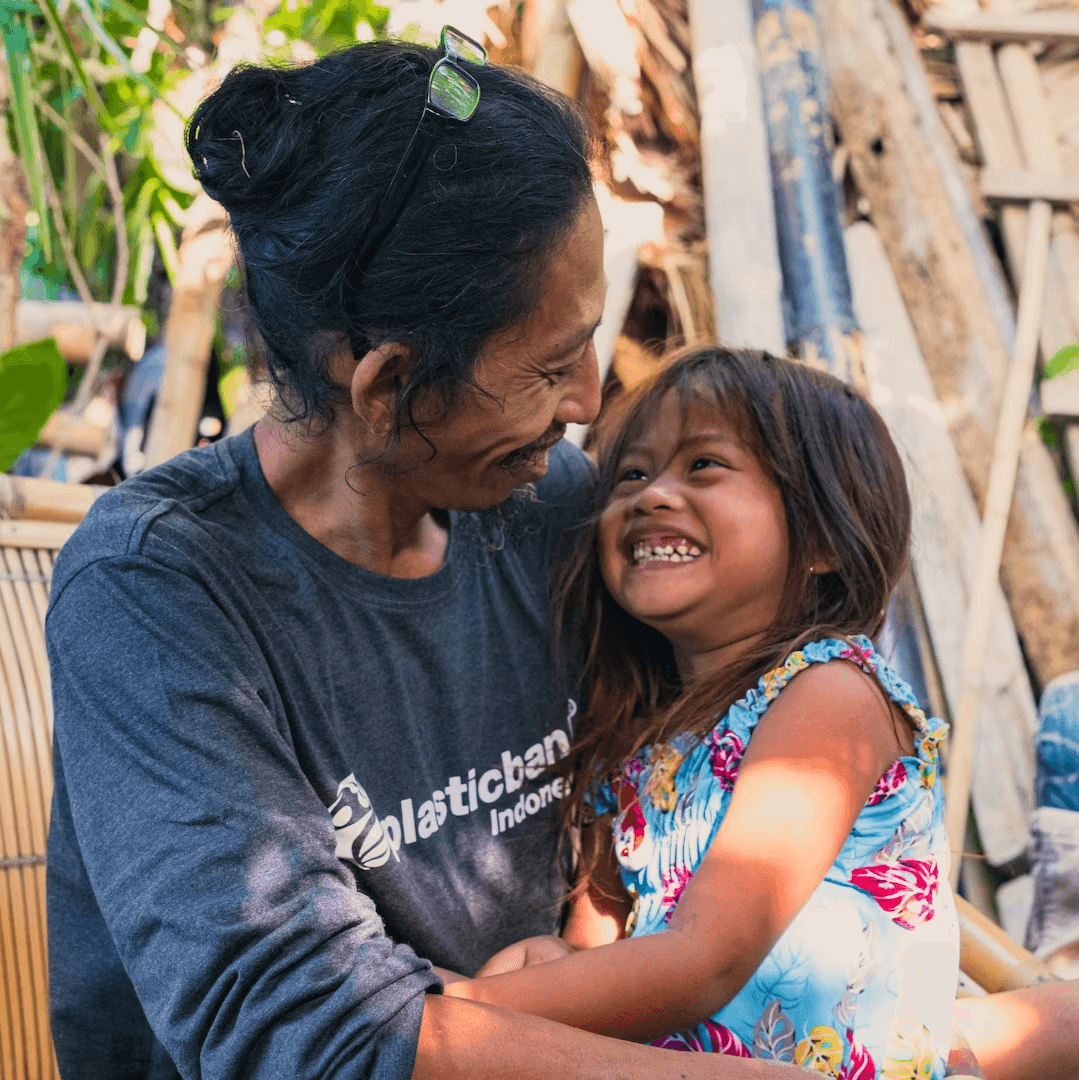 A Plastic Bank collection member in Indonesia smiling with a child.